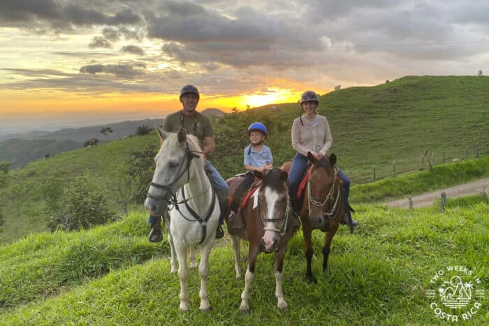 A family on horses posing in front of sunset