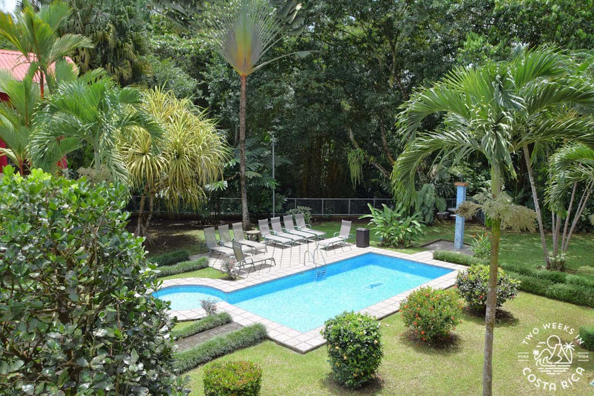 a pool with gardens and thick forest in the backdrop