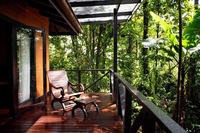 A wooden deck with a rocking chair looking out to the forest