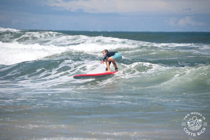 a kid practicing surfing with an instructor in costa rica