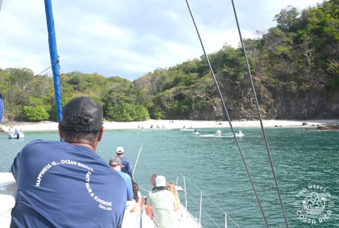 people on a boat looking at a white sand beach