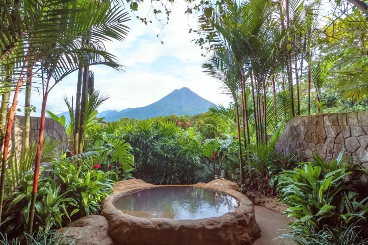 a hotel room patio with jacuzzi and a volcano in the distance