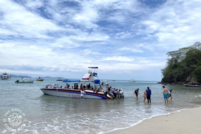 people getting off a speedboat on the shore at tortuga island